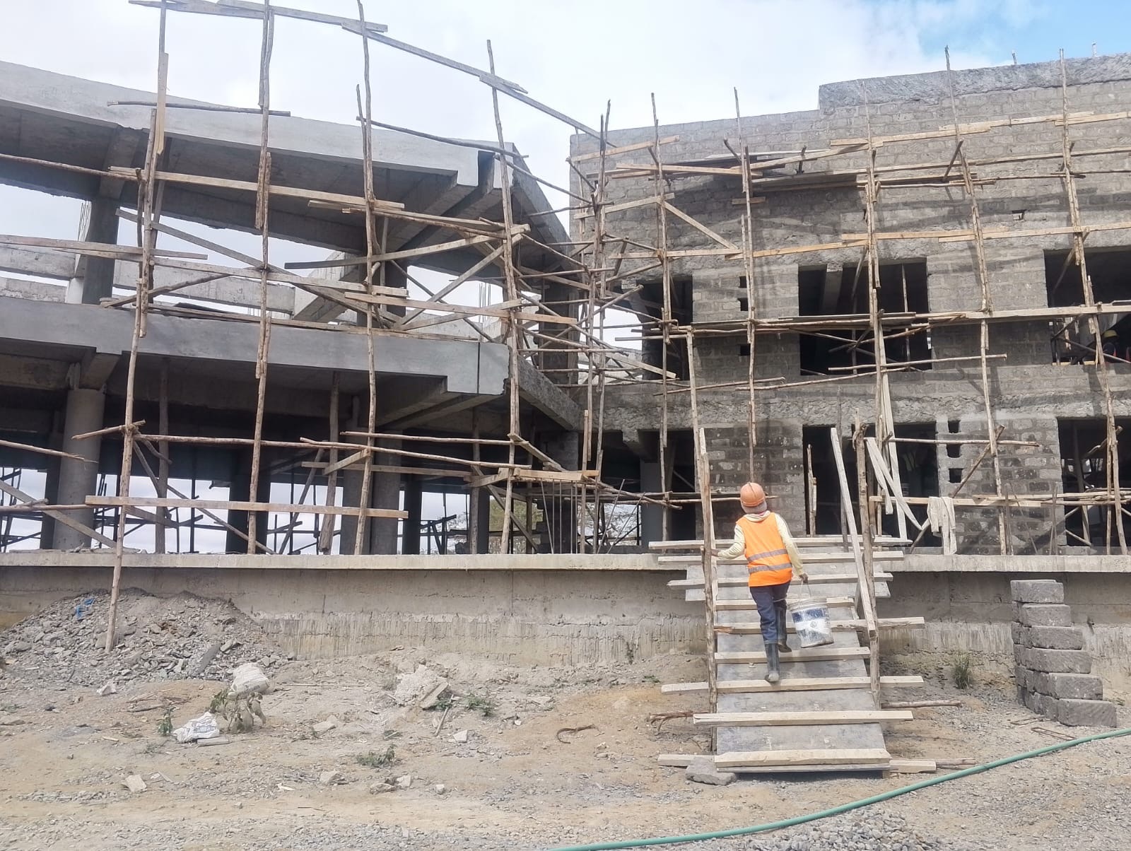 Reinforced-concrete frame of a multi-storey building under construction supervision, with timber-propped formwork and scaffolding in place.